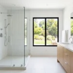 Clean bright bathroom with white tiles and glass shower door showing good ventilation to prevent mold