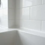 Clean white silicone caulk line along a bathtub and tiled shower wall