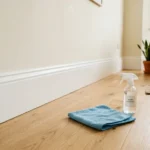 Clean white baseboards with a microfiber cloth on a hardwood floor